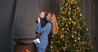 Ebeveyn ve küçük çocuk içeride noel ağacının yanında birlikte oynuyorlar. Mutlu noeller ve mutlu tatiller. Neşeli anne ve tatlı kızı.