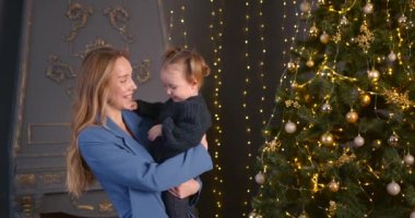 Ebeveyn ve küçük çocuk içeride noel ağacının yanında birlikte oynuyorlar. Mutlu noeller ve mutlu tatiller. Neşeli anne ve tatlı kızı.