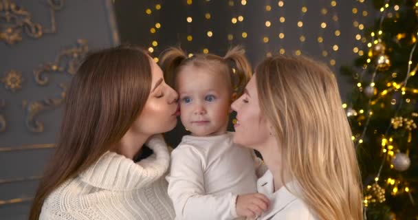 母親と叔母または2人の姉妹は小さな子供とキス クリスマスの装飾部屋 家族のお祝い 結合の概念 — ストック動画