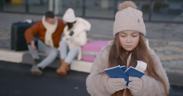 Urocza Córeczka Trzymająca Paszporty Biletami Młodymi Szczęśliwymi Rodzicami Siedzącymi Walizkach — Wideo stockowe