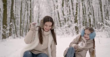 Noel tatili. Ailece ormanda kış yürüyüşü. Çocuk büyütmek, aile alışkanlıkları. Anne ve kızı, soğuk havada, kışın ormanda eğleniyorlar. Anneler kucaklaşır.