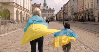 Anne ve kızı ellerinde Ukrayna 'nın geleneksel mavi ve sarı bayraklarını tutuyorlar. Aile, birlik, destek. Ukraynalılar savaşa karşıdır. Kadın ve çocuk.
