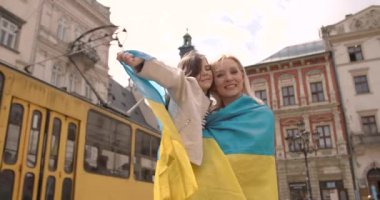 Anne ve kızı ellerinde Ukrayna 'nın geleneksel mavi ve sarı bayraklarını tutuyorlar. Aile, birlik, destek. Ukraynalılar savaşa karşıdır. Kadın ve çocuk.