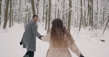 İyi tatiller. Romantik genç çift. Karlı kış günü. Noel ve tatil kavramı - mutlu çift kış ormanlarında eğleniyor..