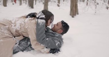 Romantik kız ve oğlan açık havada kar taneleri ile kış Tarih boyunca. Mutlu çift yatıyordu aşağı ve öpüşme kar.