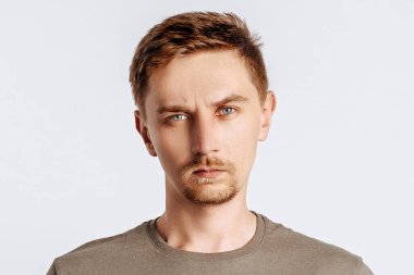 Sakallı yakışıklı esmer adam beyaz soyutlanmış arka plandan memnun değil.