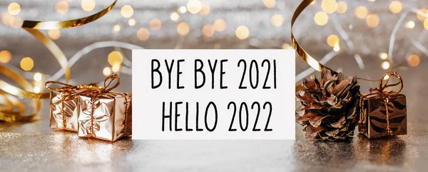 Merhaba 2022. Güle güle 2021. Zarf, hediyeler ve beyaz arka planda altın kurdele.