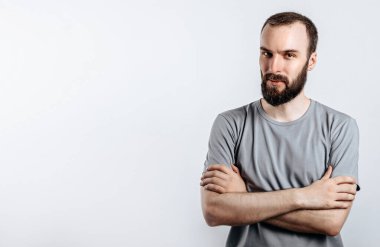 Beyaz arka planda kollarını çapraz yapmış yakışıklı, vahşi esmer bir adamın portresi. Kişi yakında yeni bir işletme sahibi olacak..