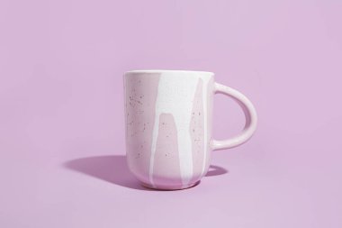 Mor arka planda tasarlanmış bir kupa. El yapımı seramik konsepti