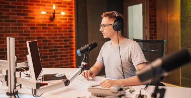 DJ programı sunar ve radyo istasyonunda izleyicilerle iletişim kurar. Sunucu haberleri okur. Erkek bir radyo sunucusu mikrofona konuşur ve bir podcast kaydeder.