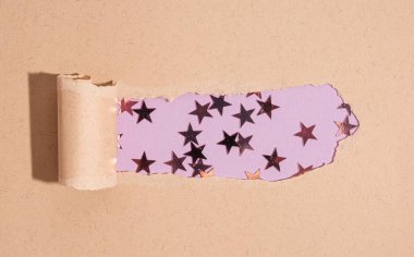 Mor arkaplanda mor yıldız şekilli parıltılı yırtık bir kağıt parçası. Tatil, doğum günü, düğün, yeni yıl, Noel, parti, kutlama konsepti