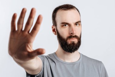 Karşıdaki kameraya bakıp beyaz arka planda reklam için yeri olan jestleri durdurun derken kaşlarını çatan yakışıklı bir gencin portresi.