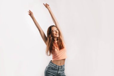 Güzel bir genç kız gülümsüyor ve kollarını kaldırıyor ve beyaz izole bir arka planda kameraya bakarak gülüyor. Pozitif esmer kadın. Nazik bak. Güzel surat.