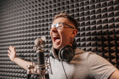 The vocalist sings in the studio in a microphone. Man in headphones writes a podcast, an audiobook. Artist, recording an album, working with the label. Announcer records a speech at a radio station clipart