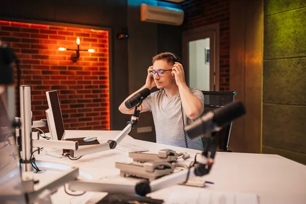 DJ programı sunar ve radyo istasyonunda izleyicilerle iletişim kurar. Sunucu haberleri okur. Erkek bir radyo sunucusu mikrofona konuşur ve bir podcast kaydeder.