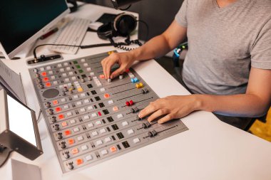 Ses yapımcısı karıştırma masasında çalışıyor. DJ programı sunar ve radyo istasyonunda izleyicilerle iletişim kurar.