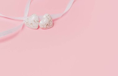 Pembe arka planda geniş kurdeleli bir kalp şekli.