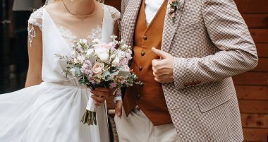 Gelin ve damat düğün gününde bir buket gül çiçeğiyle kucaklaşır ve sevgiyi gösterir