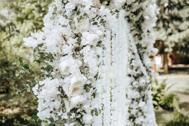 Doğada bir düğün töreni için beyaz çiçeklerle süslenmiş kemer.