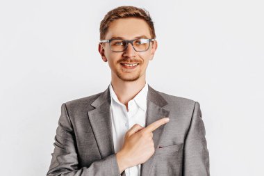 Gözlüklü yakışıklı esmer adam, beyaz izole edilmiş arka planda parmağıyla işaret ediyor.