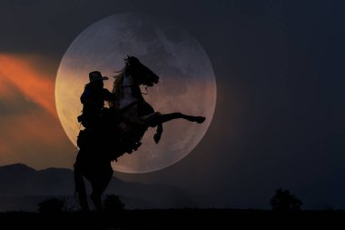 Arka planda ay olan at sırtında kovboy silueti.