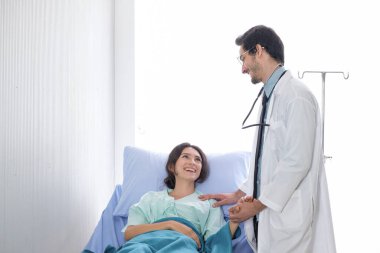 Beyaz erkek doktorlar ve kadın hastalar, hastalıktan bahsediyorlar ve hastanenin koğuşunda notlar alıyorlar.