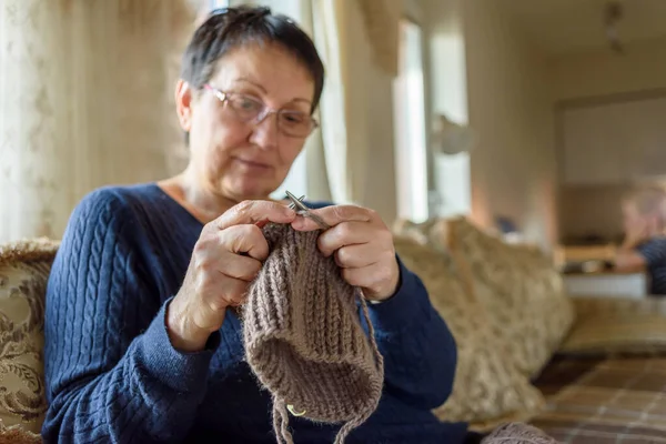 Mature woman knitting hat and relaxing