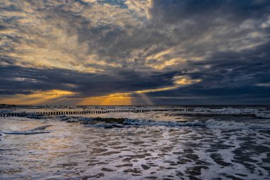 Batan güneşin ışınları deniz kıyısındaki plajları aydınlatıyor.