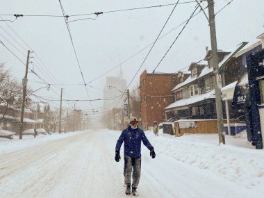 Toronto, Canada - 17 January 2022: lonely man walking along snow covered street during major winter storm
