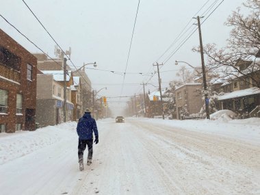 Toronto, Canada - 17 January 2022: lonely man walking along snow covered street during major winter storm