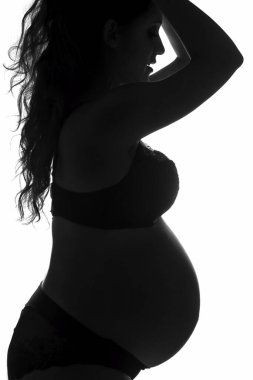 Karnı şişmiş hamile bir kadının profili. Genç bir kadının hamileliği, arka plandaki profil..