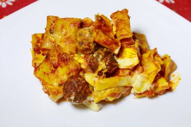 Fırında pişirilmiş makarna, domates sosu, köfte ve yumurta, yemeye hazır. Porselen tabakta fırında makarna..