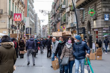 Napoli, İtalya - 24 Aralık 2021: Tarihi merkezin bir caddesinde yoğun bir kalabalık, covid-19 sağlık acil durumu nedeniyle koruyucu maskeler takarak yürüyor.