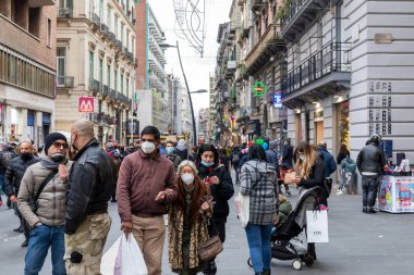 Napoli, İtalya - 24 Aralık 2021: Tarihi merkezin bir caddesinde yoğun bir kalabalık, covid-19 sağlık acil durumu nedeniyle koruyucu maskeler takarak yürüyor.