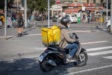 Napoli, İtalya - 25 Mart 2022 Glovo, çocuk özel termal sırt çantasında scooterla eve yiyecek getiriyor..
