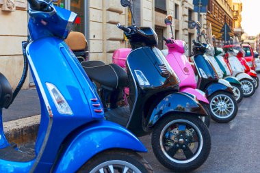 Bir dizi renkli Vespa scooter 'lar cadde boyunca arka arkaya park edilmiş, şehirde scooter kiralama yeri..