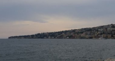 Napoli 'nin rıhtımı, İtalya. Posillipo Tepesi 'nin ufuk çizgisi ve yerleşim binaları olan şehir manzarası.