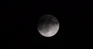 Full moon at night. The illuminated face of the moon is wrapped in a cloud cover that covers it in a veiled way.