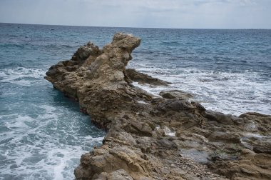 İspanya 'nın Alicante bölgesindeki Campello kasabasında kayalar, dalgalar ve köpüklerle dolu bir sahil.