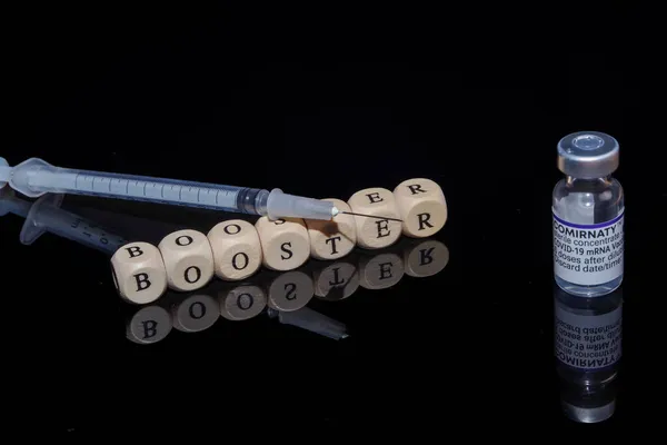Bamberg, Alemania - 16.11.2021. Cubos de letras forman la palabra refuerzo, BioNTech-Pfizer Comirnaty vial original y jeringa — Foto de Stock