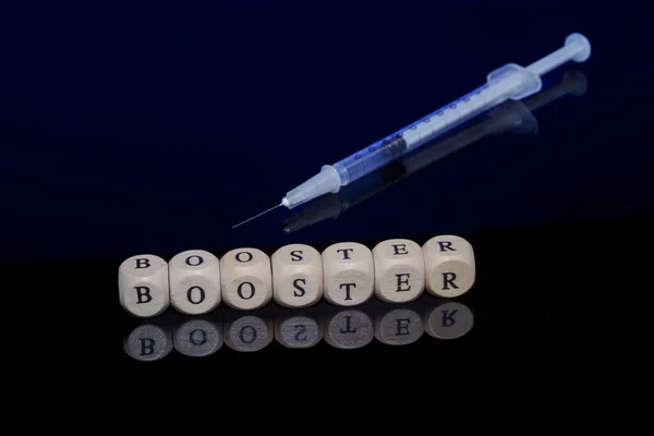 Bamberg, Německo - 16.11.2021. Kostky s nápisem Booster a očkovací stříkačka proti černému reflexnímu pozadí — Stock fotografie