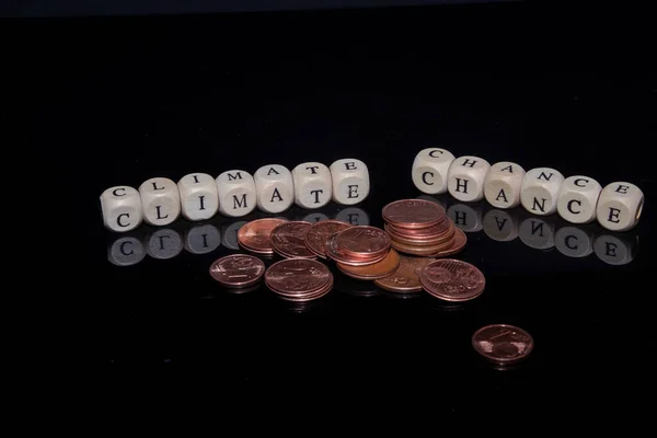 Buchstabenwürfel bilden die Worte Climate Chance vor schwarzem, reflektierendem Hintergrund, Euromünzen im Vordergrund — Stockfoto