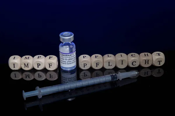 Bamberg, Alemania - 16.11.2021. Imagen conceptual vacunación obligatoria, cubos de letras, jeringa de vacunación y vial de vacunación con biontech-pfizer — Foto de Stock