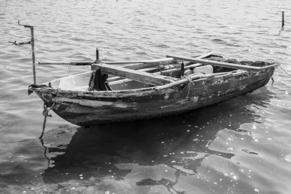 Sehr alt und verwittert, hölzernes Fischerboot auf dem Wasser, Schwarz-Weiß-Foto — Stockfoto