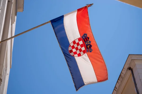 Bandera croata fotografiada desde abajo, enmarcada con partes de fachadas de la casa — Foto de Stock