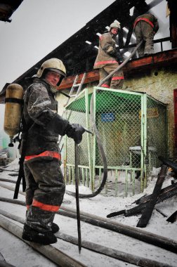 Barnaul, Rusya. 24 Aralık 2019. İtfaiyeciler soğuk bir kış gününde evin çatısındaki yangını söndürürler.