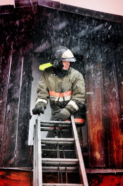 Barnaul, Rusya. 24 Aralık 2019. İtfaiyeciler soğuk bir kış gününde evin çatısındaki yangını söndürürler.