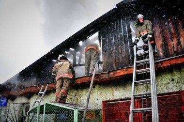 Barnaul, Rusya. 24 Aralık 2019. İtfaiyeciler soğuk bir kış gününde evin çatısındaki yangını söndürürler.