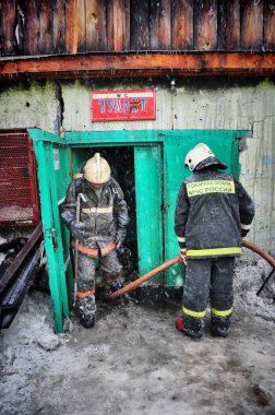 Barnaul, Rusya. 24 Aralık 2019. İtfaiyeciler soğuk bir kış gününde evin çatısındaki yangını söndürürler.