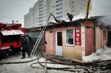 Barnaul, Rusya. 24 Aralık 2019. İtfaiyeciler soğuk bir kış gününde evin çatısındaki yangını söndürürler.